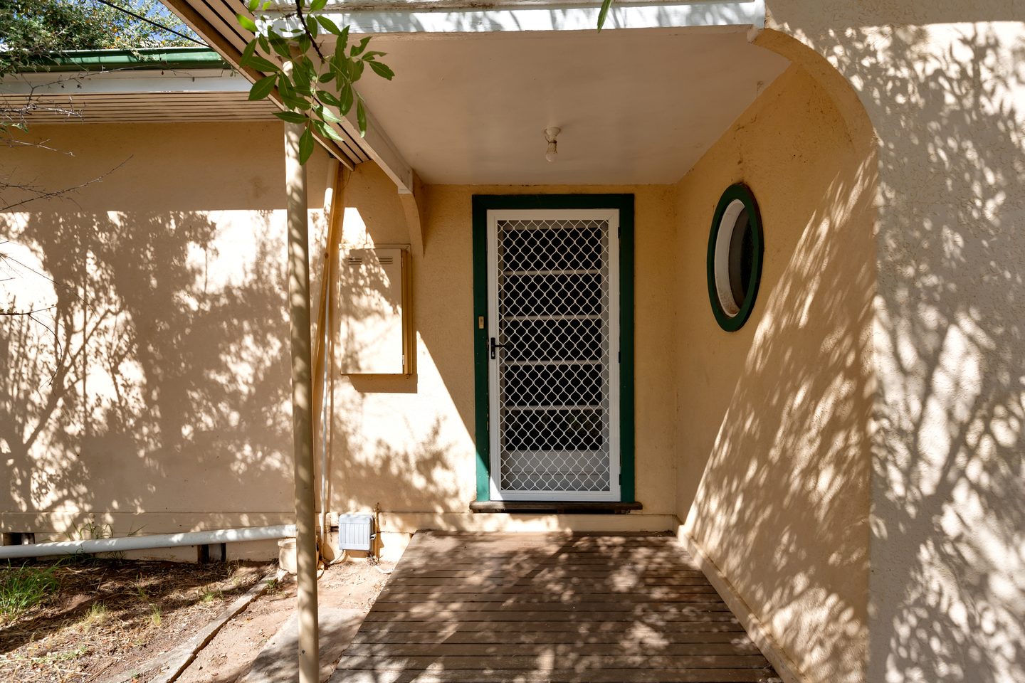 Shaded entrance porch with green trim and a round window