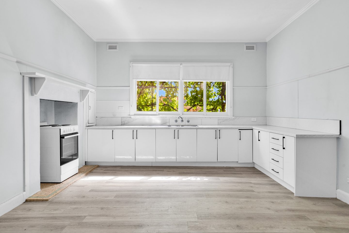 Kitchen with white cabinetry and a broad window over the sink