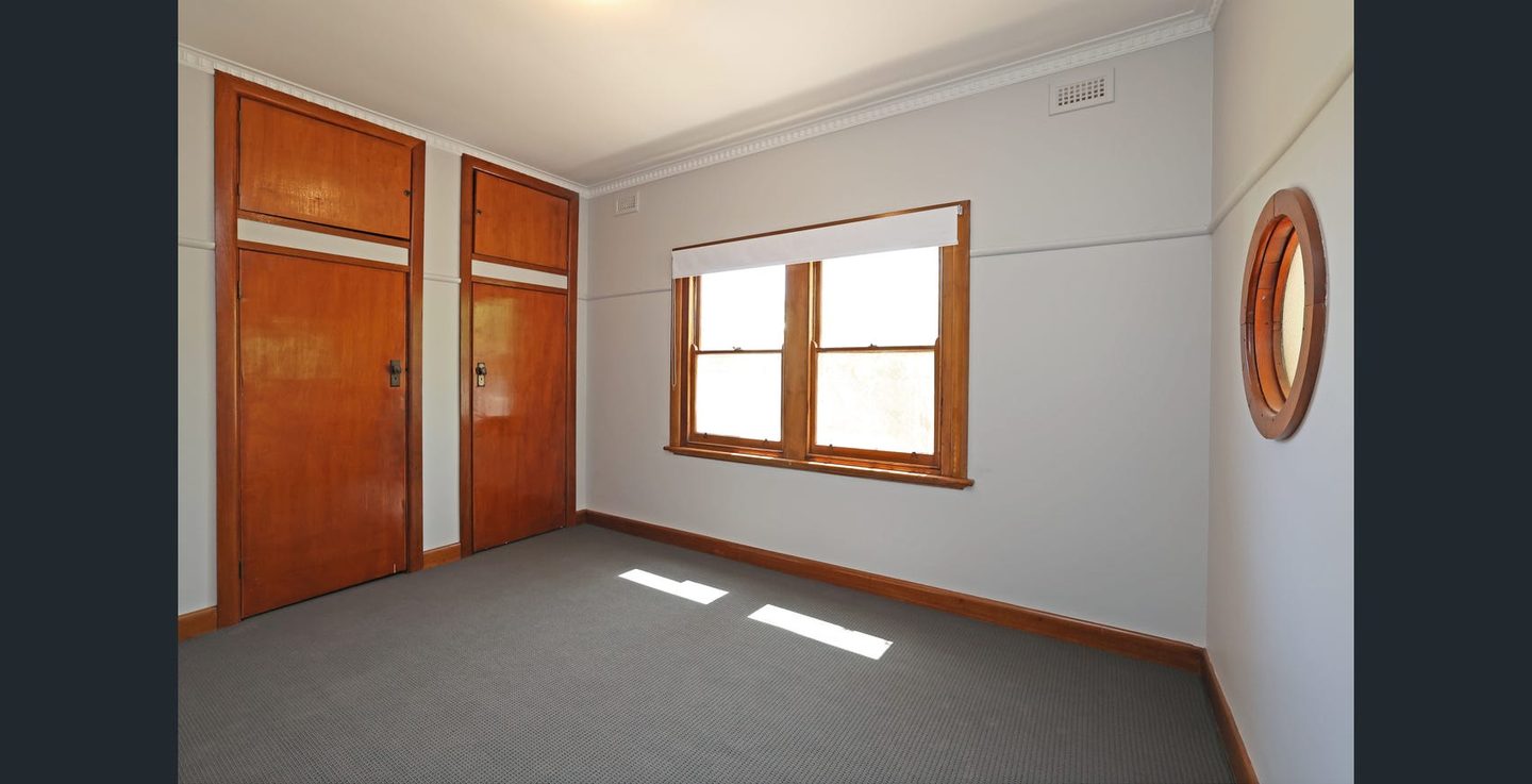 Bedroom with built-in robes and timber-framed windows