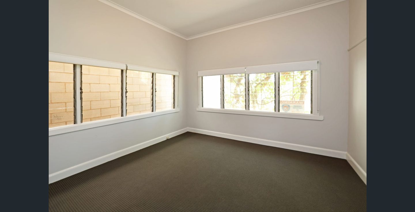 Carpeted bedroom with windows on adjoining walls
